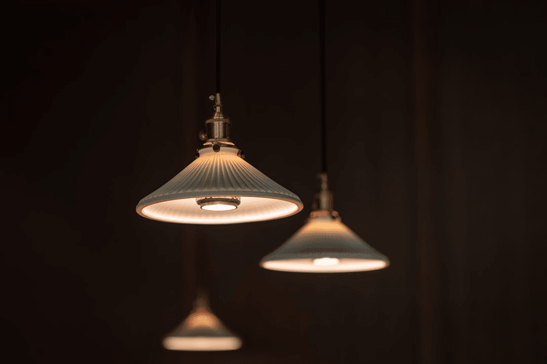 Lámparas colgantes de diseño cerámico con luz cálida en un fondo oscuro.